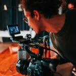 Man filming on set with professional video camera in studio setting.